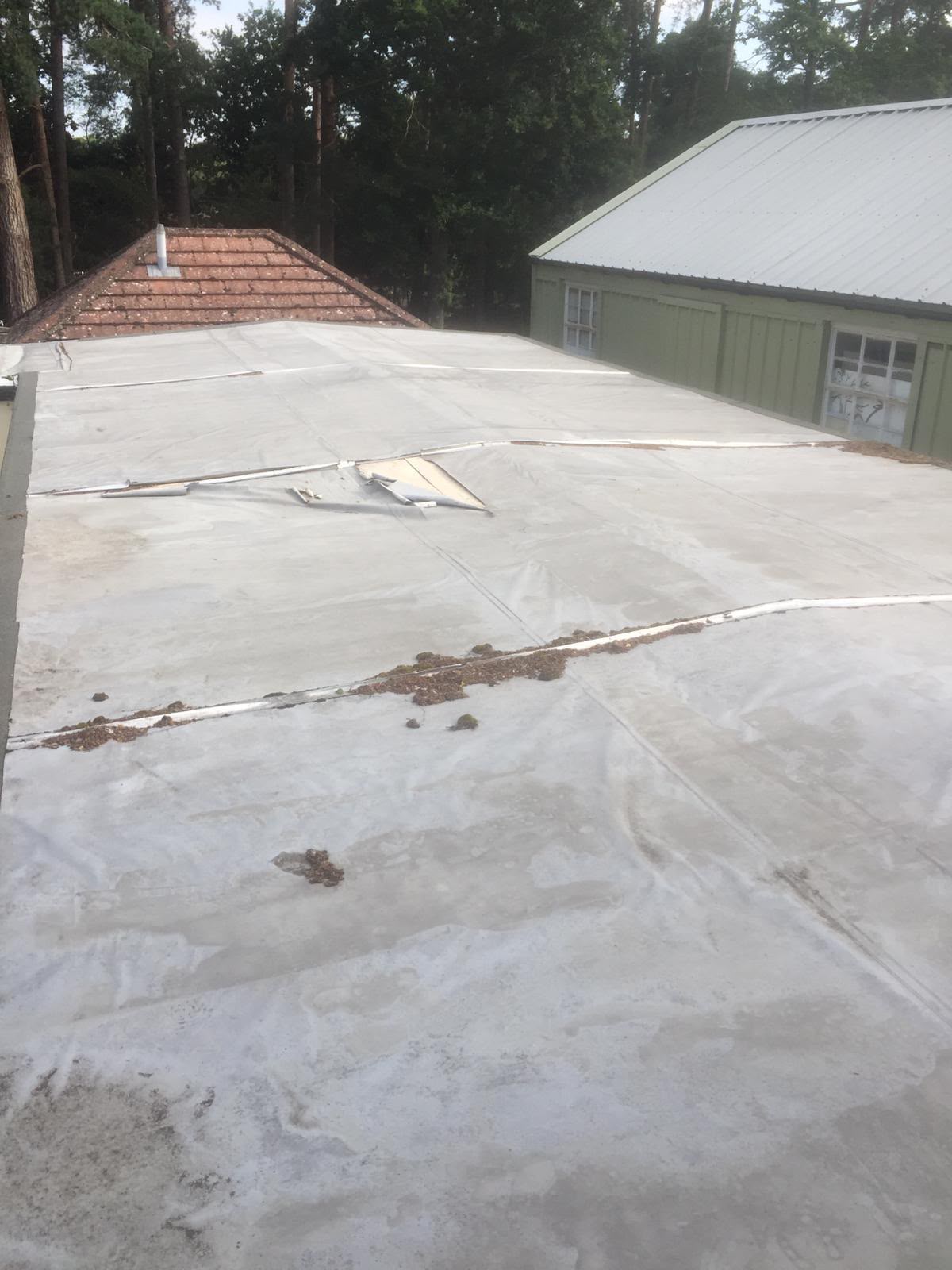 Old tired flat roof before replacement — worn membrane and debris
